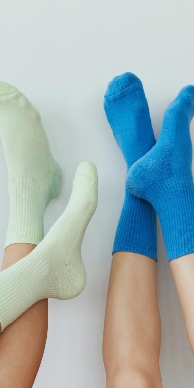 Close-up of colorful socks on legs raised against a light wall, showcasing minimalist style.