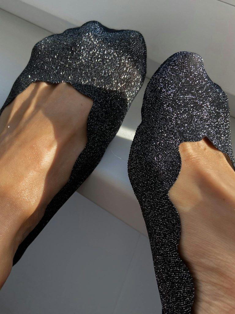 Close-up of feet in shimmering black footwear highlighting fashion style.