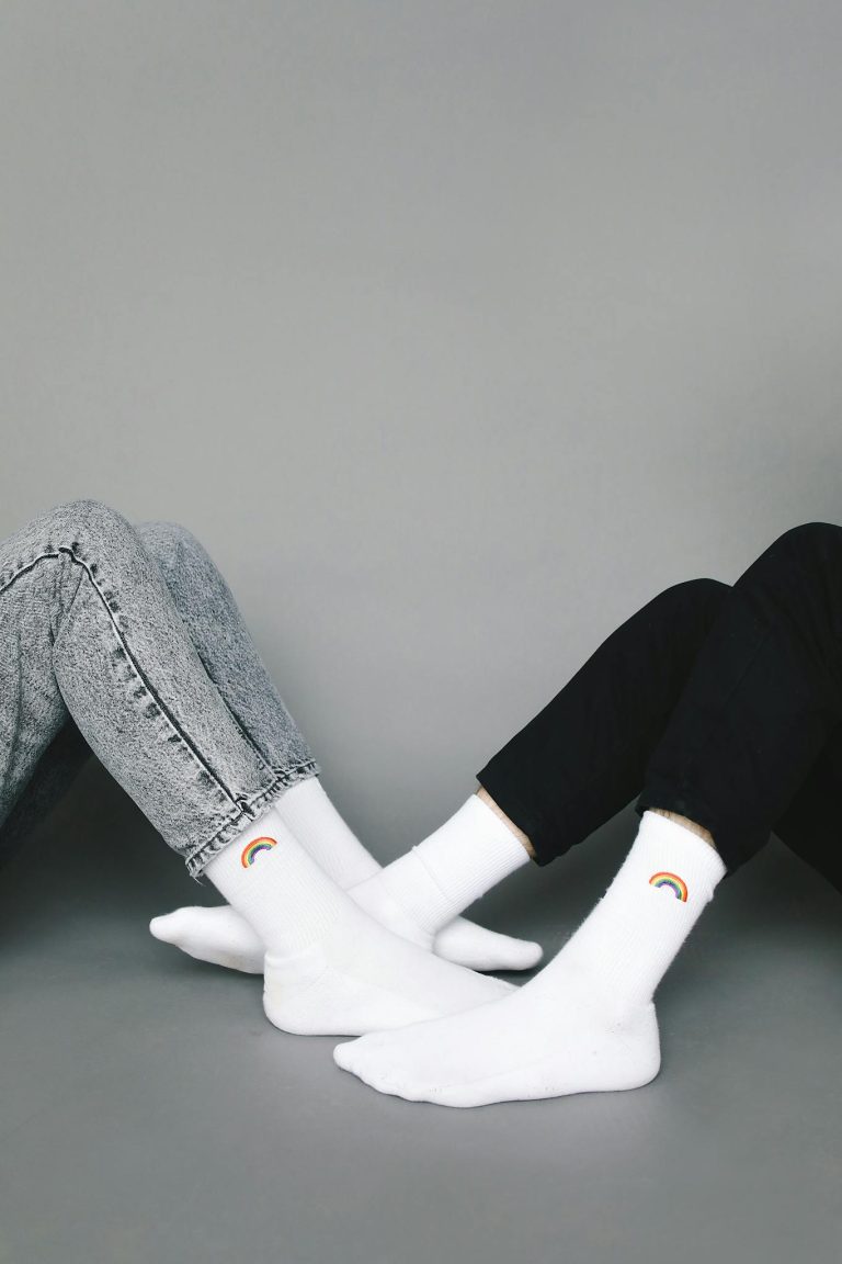 Studio photo of two people wearing rainbow socks, showcasing simple yet stylish fashion.