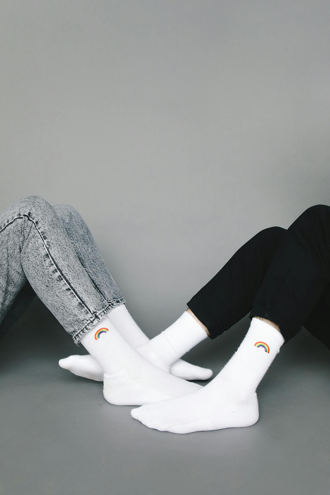 Studio photo of two people wearing rainbow socks, showcasing simple yet stylish fashion.