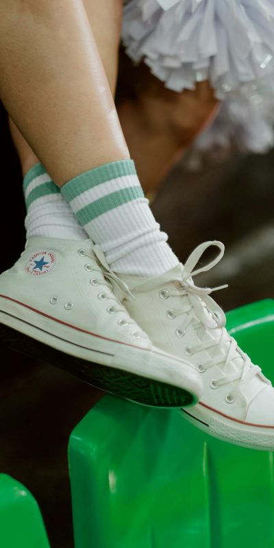 White sneakers with green-striped socks on a bright green surface.