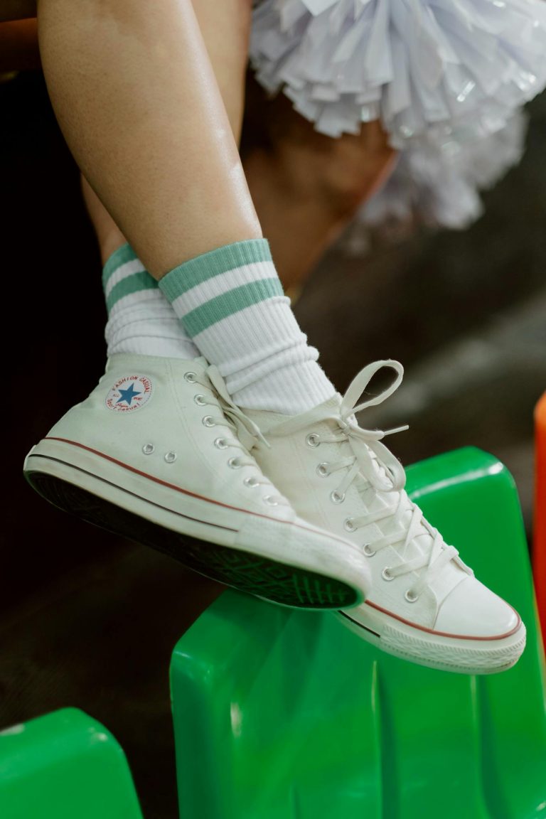 White sneakers with green-striped socks on a bright green surface.